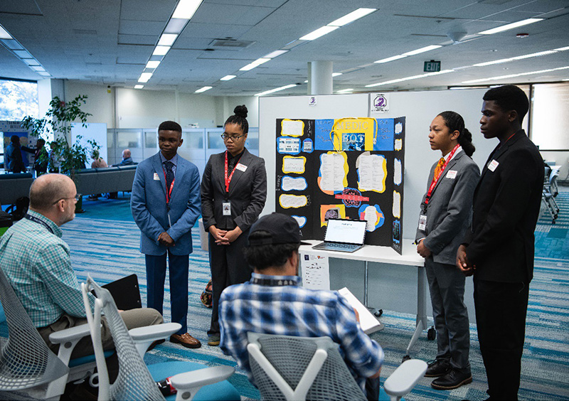 Supercomputing Challenge students presenting a project poster with mentors and judges.